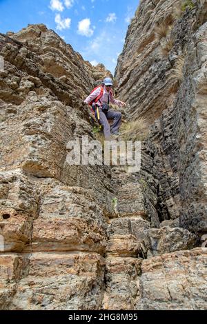 Donna che scende scogliere sulla baia di Moorina lungo la pista di Cape Queen Elizabeth Foto Stock