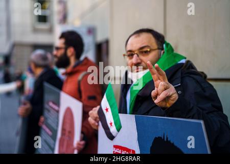 19 gennaio 2022, Hessen, Francoforte sul meno: Un attivista siriano fa il 'segno della Vittoria' davanti al tribunale. Un altro processo per crimini contro l'umanità nel paese di guerra civile della Siria inizia mercoledì alla Corte Regionale superiore. L'imputato è un medico di 36 anni. Il procedimento penale federale lo accusa di tortura e di uccisione premeditata di un prigioniero. Nel 2011 e nel 2012, avrebbe inflitto gravi danni fisici e mentali ai prigionieri in un ospedale militare e in una prigione militare di intelligence a Homs. Foto: Andreas Arnold/dpa Foto Stock