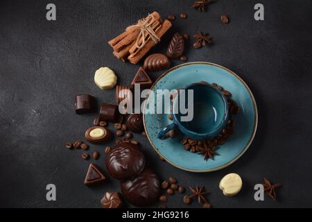 Tazza di caffè, fagioli, cioccolato su vecchio tavolo da cucina assortimento di dolci al cioccolato fondente, bianco e latte, zefiro (zephyr). Spezie, cannella. Foto Stock