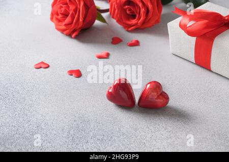 San Valentino due dolci a forma di cuore e regalo romantico, bouquet di rose rosse. Primo piano. Foto Stock