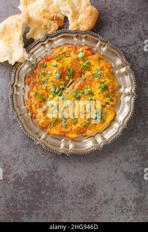 Ricette indiane Masala Omelet con verdure fresche in primo piano nel piatto sul tavolo. Vista dall'alto verticale Foto Stock