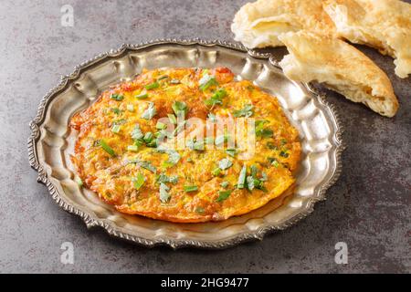 Popolare ricetta indiana nepalese Masala Omelet servita sul piatto sul tavolo. Orizzontale Foto Stock