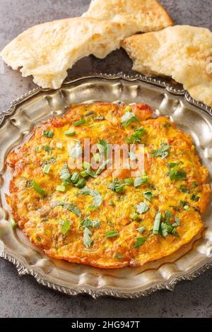 Masala Omelet in stile indiano famoso cibo di strada di Mumbai primo piano nel piatto sul tavolo. Verticale Foto Stock