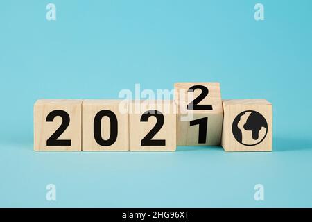 Blocchi di legno con numero variabile 2021 2022. Concetto di nuovo anno. Spazio di copia. Blocco di cubo flipping da 2021 a 2022 su sfondo blu, cubi di legno Foto Stock