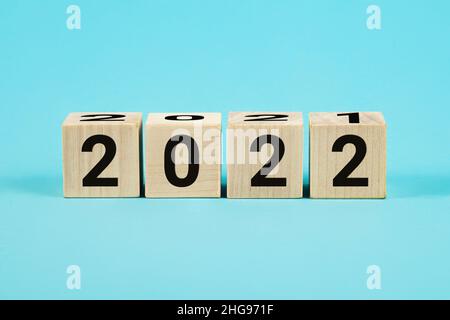 Blocchi di legno con numero variabile 2021 2022. Concetto di nuovo anno. Spazio di copia. Blocco di cubo flipping da 2021 a 2022 su sfondo blu, cubi di legno Foto Stock