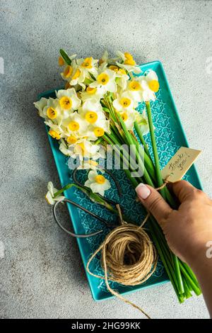 Mano della donna che raggiunge per un mazzo di fiori narciso con un tag di ringraziamento Foto Stock