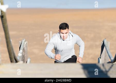 Allenatore sportivo latino forza su una scala in spiaggia Foto Stock