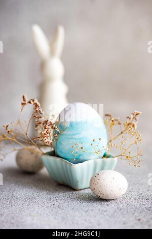 Decorazioni dipinte di coniglietto pasquale e uovo di Pasqua su un tavolo con fiori secchi Foto Stock
