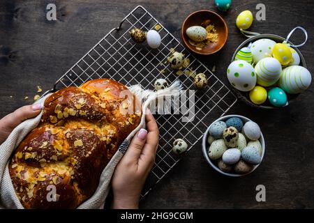 Primo piano di una donna che mette un tradizionale tsoureki pane pasquale con mandorle su una griglia di raffreddamento Foto Stock