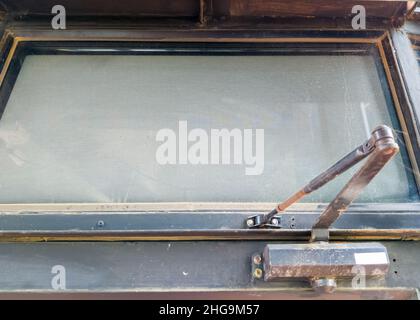 Primo piano dei chiudiporta sporchi con la macchia di ruggine per l'apertura verso l'area esterna del ristorante, vista frontale per lo spazio copia. Foto Stock