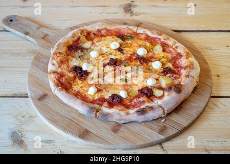 Deliziosa pizza artigianale a legna con pesto, cipolle caramellate, patate e crema acida Foto Stock