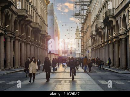 Vista retroilluminata di via Roma nel centro storico di Torino con persone che camminano e pedalano durante le vacanze di Natale, Piemonte, Italia Foto Stock