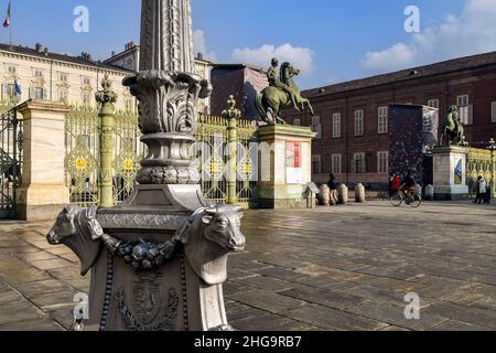 Una lampada da strada decorata con teste di corone, simbolo di Torino, di fronte alla porta di Palazzo reale in una soleggiata giornata invernale, Piemonte, Italia Foto Stock