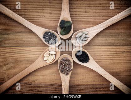 Set di semi organici in cucchiai su sfondo di legno, cibo naturale sano e concetto di nutrizione Foto Stock