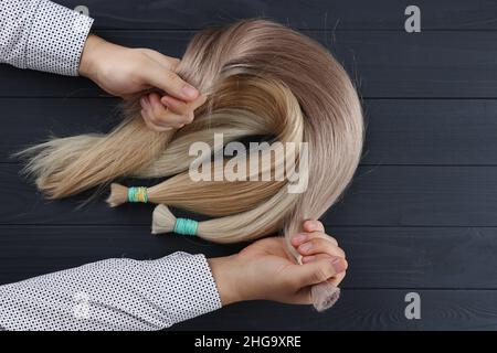 La mano maschio tiene sezioni di capelli per extension.Photography dall'alto. Foto Stock