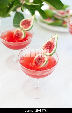 Bevanda rossa con ghiaccio. Bevande alcoliche decorate con frutta fresca di fico su sfondo bianco. Campari aperol drink Foto Stock