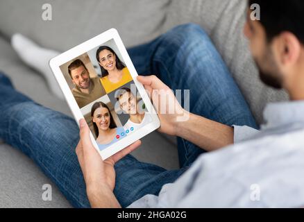 Un uomo che si agghiacciava con un tablet digitale, con una festa online Foto Stock