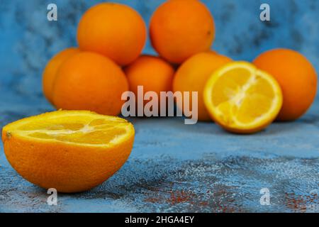 Arance su sfondo blu testurizzato, vista laterale di un sacco di pile di arancio fresco. Nessuna gente. Foto Stock