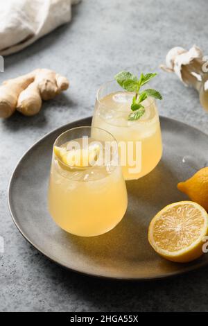 Kombucha in vetro con limone e zenzero su sfondo grigio con spazio per la copia. Primo piano. Formato verticale. Foto Stock