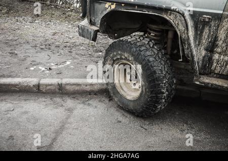 Ruota sporca di un'auto SUV parcheggiata su strada Foto Stock