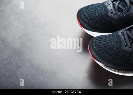 Scarpe da running nere con rete e lacci neri da vicino su sfondo scuro. Vista dall'alto delle sneaker sportive. Foto Stock