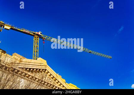 Gru in cima a un edificio del centro, contro un cielo blu brillante Foto Stock