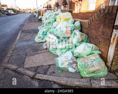 Un sacco di sacchi di riciclaggio completo in una strada residenziale, pronto per la raccolta da parte dei raccoglitori di rifiuti, cumulo di sacchi di rifiuti sul marciapiede. Swansea, Galles, Regno Unito - 17 gennaio 20222 Foto Stock