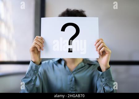 Businesswoman Holding Paper con punto interrogativo davanti alla reception in ufficio Foto Stock