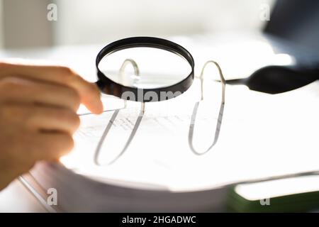 Avvocato che esamina la carta utilizzando lente d'ingrandimento. Indagine sulle frodi fiscali Foto Stock