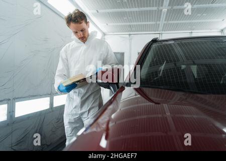 Il colorista automatico nella camera di verniciatura seleziona il colore della vernice per auto con campioni Foto Stock