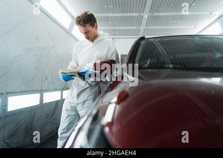 Il colorista automatico nella camera di verniciatura seleziona il colore della vernice per auto con campioni Foto Stock