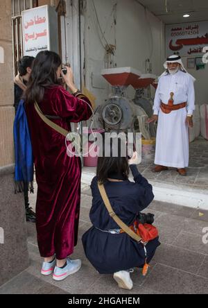 Turisti che scattano foto di un uomo saudita con la tradizionale janbiya, provincia di Najran, Najran, Arabia Saudita Foto Stock