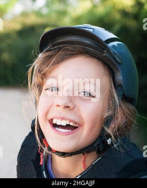 Felice bambina in casco per cavalcare Foto Stock