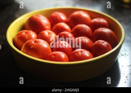 Pomodori tagliati pronti a tenerli in forno per preparare la pasta con salsa rossa. Pomodori rossi in piatto giallo. Foto Stock