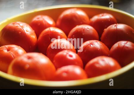 Pomodori tagliati pronti a tenerli in forno per preparare la pasta con salsa rossa. Pomodori rossi in piatto giallo. Foto Stock