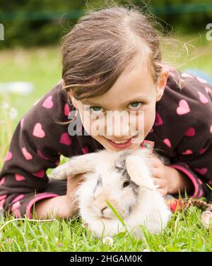 Giovane ragazza sdraiata sul prato con il suo coniglio Foto Stock