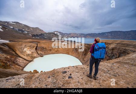 Escursionista al lago cratere Viti e Oeskjuvatn nel cratere del vulcano Askja, massiccio montano Dyngjufjoell, Islanda Foto Stock