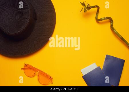Viaggi. Cappello, 2 passaporti, biglietti aerei e bicchieri su sfondo arancione. Spazio vuoto per il testo. Sconti sui viaggi. Vacanze, estate. Foto Stock