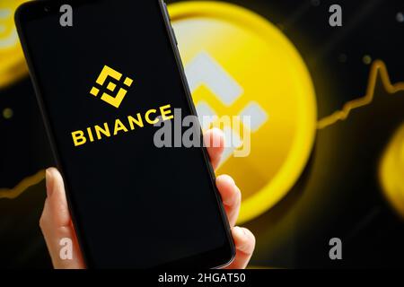 Ucraina, Odessa - 9 ottobre 2021: Tenere a mano il cellulare con l'app Binance in esecuzione sullo schermo dello smartphone con il logo Binance sullo sfondo. Binance è una piattaforma di scambio e scambio di criptovaluta Foto Stock