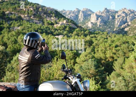 Motociclista scattare una foto con uno smartphone in natura. Foto Stock