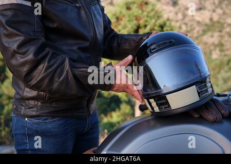 Un uomo irriconoscibile che mette il casco sulla moto Foto Stock