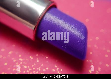 Rossetto viola e blu con scintille su sfondo rosa. Lucentezza, moda, sconti su rossetto. Colori brillanti, cosmetici per l'estate. Foto Stock