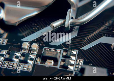 Primo piano. Giovane uomo che ripara la scheda madre dal PC. Officina di riparazione. Lavorare con gli strumenti. Hardware del computer. Lente di ingrandimento. Saldatore. Dispositivo digitale Foto Stock