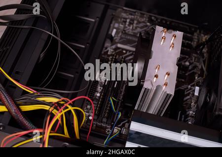 Un uomo a casa raccoglie, disassembla un computer. Le mani di un uomo tengono i fili, collegano i fili. Raccolta di un computer per i professionisti, un computer da gioco Foto Stock