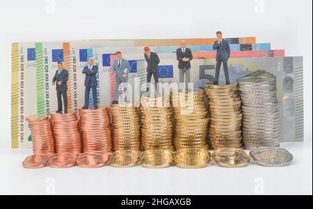 Pile di monete, monete in cent, monete in euro, figure in miniatura, foto manager simbolo salario uomini d'affari, foto studio Foto Stock