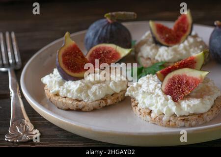 Piatto per la colazione sano per dieta o dieta con cracker di riso marrone senza glutine sormontato da formaggio caserma e fichi freschi Foto Stock