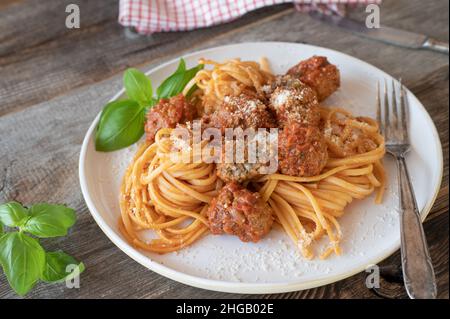 Piatto tradizionale italiano con spaghetti e polpette. Servito con una deliziosa salsa di pomodoro su un piatto di legno Foto Stock