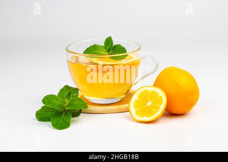 Tazza di vetro trasparente con tè aromatico, foglie di menta e fetta di limone isolato su sfondo bianco. Parte del set. Foto Stock