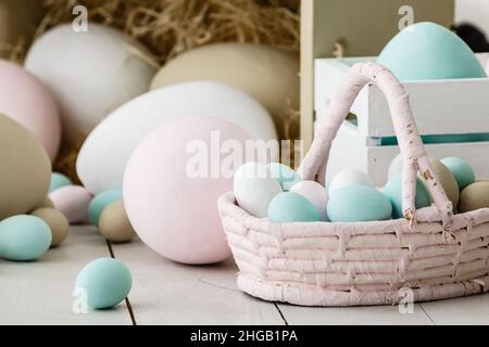 Composizione pasquale, uova di coniglio e di pollo bianco nel cestino di vimini, su sfondo chiaro per il testo Foto Stock