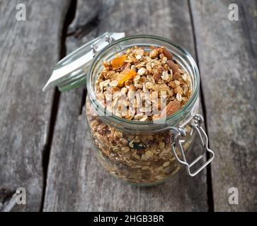 Granola nel vasetto di vetro sul tavolo di legno Foto Stock